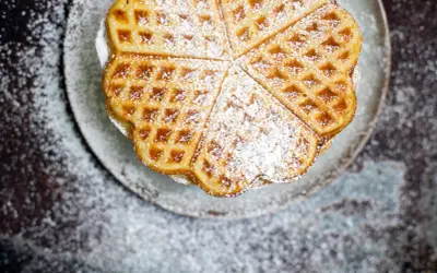 Herzförmige Waffeln, bestäubt mit Puderzucker, sehen aus wie aus einem perfekten Waffeln Rezept.