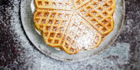 Herzförmige Waffeln, bestäubt mit Puderzucker, sehen aus wie aus einem perfekten Waffeln Rezept.