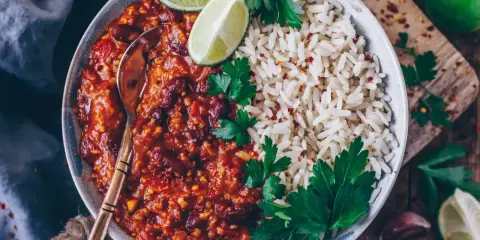 Herzhaftes Chili sin Carne mit Kidneybohnen, Reis, Limettenspalten und Petersilie. Ein Löffel wartet schon.