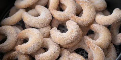 Ein Haufen frisch gebackener Vanillekipferl, bedeckt mit feinem Zucker, wartet darauf, genossen zu werden.