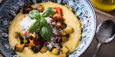 Cremige Polenta mit gebratenem Gemüse, Parmesan und Basilikum. So ist Polenta genau richtig: ein herzhaftes Gericht, das wärmt.