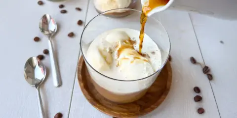 Ein heißer Espresso fließt über cremiges Vanilleeis. Ein perfekter Affogato Cafe, bereit zum Genießen.