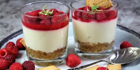 Zwei leckere Desserts im Glas mit Himbeeren und Keksen, ein Genuss für Augen und Gaumen.