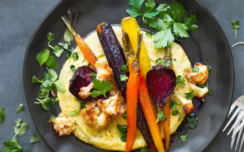 Bunte Wurzelgemüse und Blumenkohl auf cremiger Polenta – eine köstliche Idee, was passt zu Polenta vegetarisch.
