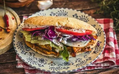 Saftiger Döner Kebab mit Fleisch, Salat, Tomaten, Zwiebeln und Rotkohl auf einem Teller. Ein leckeres Kebab Rezept zum Nachmachen.