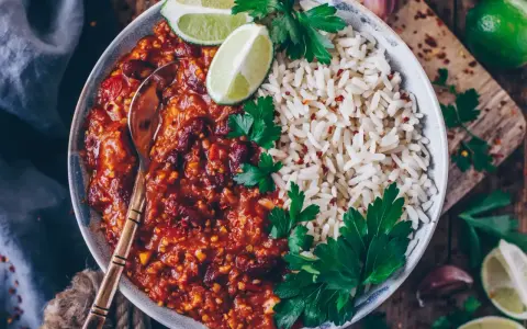 Herzhaftes Chili sin Carne mit Kidneybohnen, Reis, Limettenspalten und Petersilie. Ein Löffel wartet schon.
