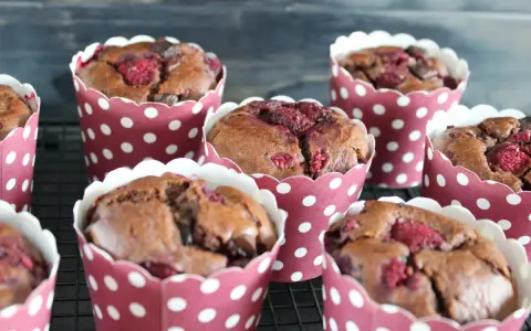 Saftige schokomuffins mit Himbeeren, gebacken in rot-weißen Pünktchen-Förmchen, warten auf ihren Genuss.