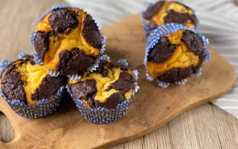 Zupfkuchen Muffins mit Schoko-Marmorierung in blauen Papierförmchen auf einem Holzbrett.