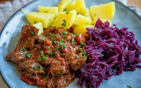 Herzhaftes Gulasch mit Kartoffeln und Rotkohl, inspiriert von Gulaschkanone Rezepten.