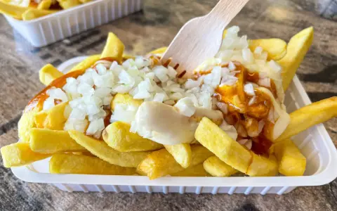 Pommes Spezial: goldgelbe Pommes mit Mayonnaise, Zwiebeln und einer würzigen Sauce, bereit zum Genuss.