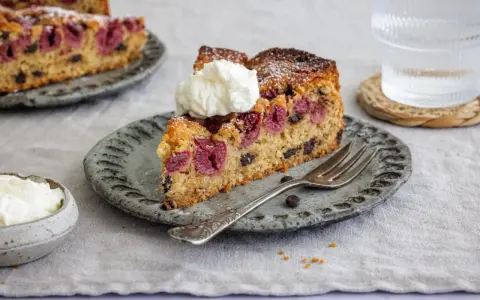 Ein Stück saftiger nusskuchen mit pudding, Kirschen und Schokostückchen, garniert mit Sahne.