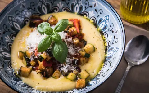 Cremige Polenta mit gebratenem Gemüse, Parmesan und Basilikum. So ist Polenta genau richtig: ein herzhaftes Gericht, das wärmt.