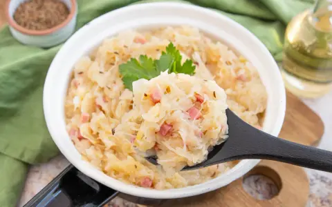 Herzhaftes Sauerkraut nach Hausfrauenart mit Speck und Kümmel, garniert mit Petersilie. Ein Löffel voller Tradition.