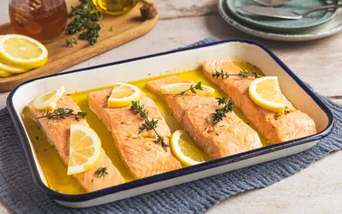 Vier Lachsfilets mit Zitrone und Thymian in einer Auflaufform, bereit für den Ofen. Perfekt für einfache Lachs Rezepte Ofen.