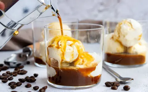 Heißer Kaffee fließt in ein Glas mit cremigem Vanilleeis. Ein köstlicher Affogato, perfekt für eine süße Erfrischung.