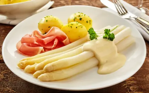 Spargel mit Sauce Hollandaise, kleinen Kartoffeln und Schinken. Eine Portion, die zeigt, wieviel Fisch pro Person auf den Teller passt, wenn man ihn durch Spargel ersetzt.