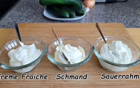 Drei Schüsseln mit cremigem Frischkäse: Crème Fraîche, Schmand und Sauerrahm. Perfekt für deutsche Rezepte.