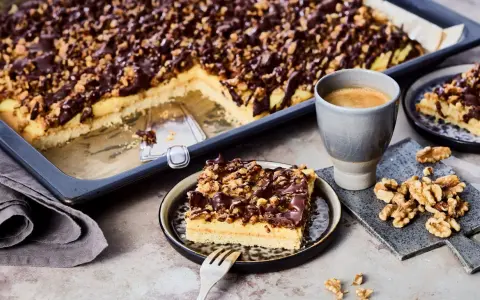 Ein Stück "friss dich dumm Kuchen" mit Schokoladen-Nuss-Decke und einer Tasse Kaffee.