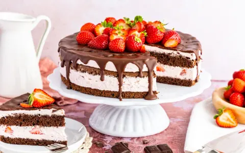 Ein saftiger Erdbeerkuchen mit Schokolade, dekoriert mit frischen Erdbeeren und Schokoladenglasur. Ein Stück ist bereits angeschnitten.