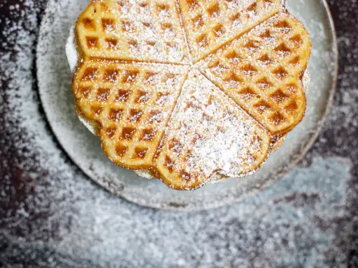 Herzförmige Waffeln, bestäubt mit Puderzucker, sehen aus wie aus einem perfekten Waffeln Rezept.
