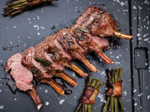 Ein perfekt gegrilltes Lammkarree mit Rosmarin und Speckbohnen. Das ganze Lamm grillen ist eine Kunst, die hier meisterhaft präsentiert wird.