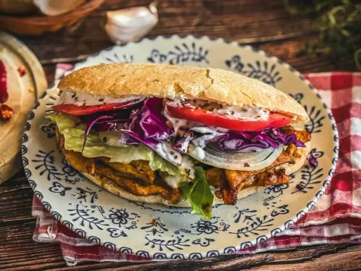 Saftiger Döner Kebab mit Fleisch, Salat, Tomaten, Zwiebeln und Rotkohl auf einem Teller. Ein leckeres Kebab Rezept zum Nachmachen.