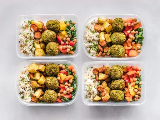 Vier Behälter mit leckeren meal prep Rezepten: Reis, gebratenes Gemüse, Falafel und bunte Paprika.
