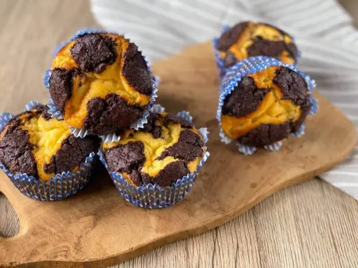 Zupfkuchen Muffins mit Schoko-Marmorierung in blauen Papierförmchen auf einem Holzbrett.