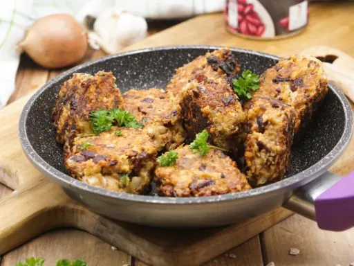 Herzhafte vegetarische Frikadellen mit Kidneybohnen und Kräutern in einer Pfanne, garniert mit Petersilie.
