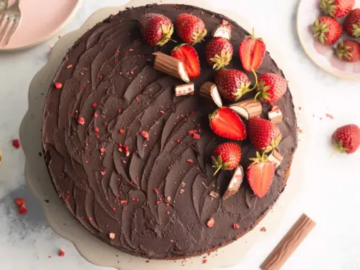 Schokoladige Yogurette Torte mit frischen Erdbeeren und Schokoriegel-Stücken verziert. Ein Traum für jeden Kuchenliebhaber!