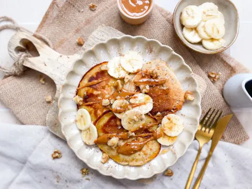 Bananen Pancakes ohne Ei, garniert mit Bananenscheiben, Nüssen und einer cremigen Sauce. Ein köstlicher Brunch-Traum!