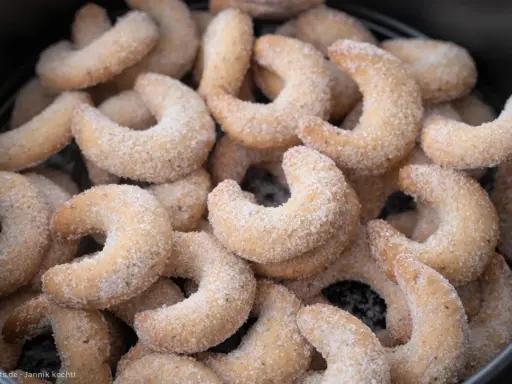Ein Haufen frisch gebackener Vanillekipferl, bedeckt mit feinem Zucker, wartet darauf, genossen zu werden.