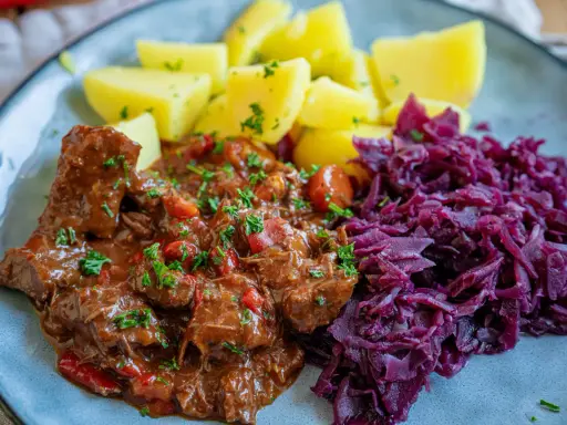 Herzhaftes Gulasch mit Kartoffeln und Rotkohl, inspiriert von Gulaschkanone Rezepten.
