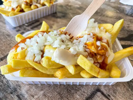 Pommes Spezial: goldgelbe Pommes mit Mayonnaise, Zwiebeln und einer würzigen Sauce, bereit zum Genuss.