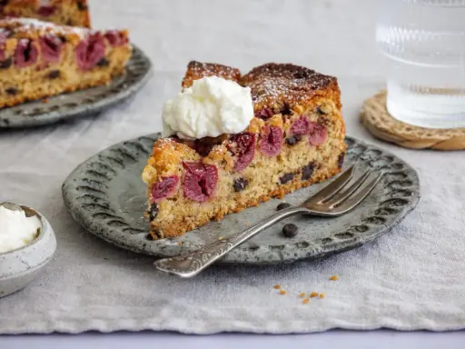 Ein Stück saftiger nusskuchen mit pudding, Kirschen und Schokostückchen, garniert mit Sahne.