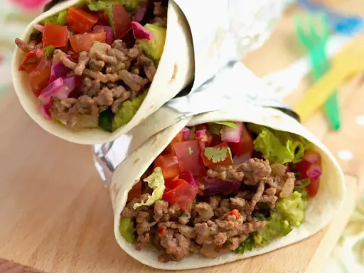 Zwei leckere wraps mit hackfleisch, Guacamole, Tomaten und roten Zwiebeln, eingewickelt in Folie.