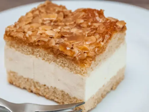 Ein Stück Kuchen mit cremiger Füllung und karamellisierten Mandeln. Der Kuchen wird zu dunkel, aber die Mandeln sind perfekt gebräunt.