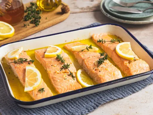 Vier Lachsfilets mit Zitrone und Thymian in einer Auflaufform, bereit für den Ofen. Perfekt für einfache Lachs Rezepte Ofen.