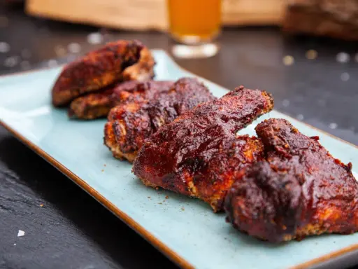 Saftige chicken wings in einer würzigen Marinade, serviert auf einem hellblauen Teller.