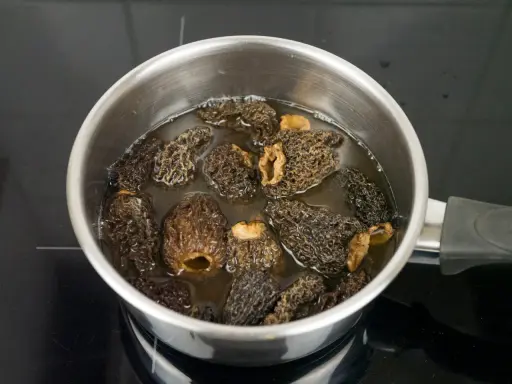 Getrocknete Morcheln werden in einem Topf mit Wasser eingeweicht, um sie für die Zubereitung vorzubereiten.