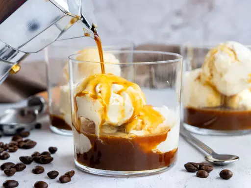 Heißer Kaffee fließt in ein Glas mit cremigem Vanilleeis. Ein köstlicher Affogato, perfekt für eine süße Erfrischung.