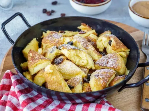 Kaiserschmarrn, fluffig und goldbraun, mit Rosinen und Puderzucker bestreut, zubereitet im Thermomix.
