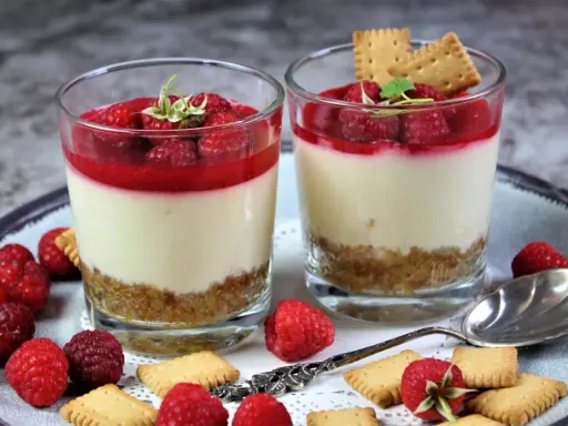 Zwei leckere Desserts im Glas mit Himbeeren und Keksen, ein Genuss für Augen und Gaumen.