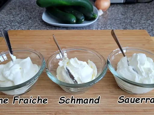 Drei Schüsseln mit cremigem Frischkäse: Crème Fraîche, Schmand und Sauerrahm. Perfekt für deutsche Rezepte.