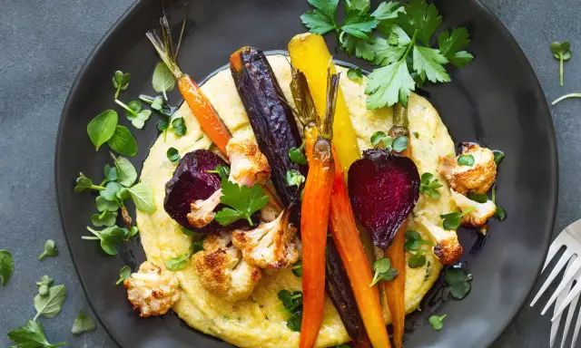 Bunte Wurzelgemüse und Blumenkohl auf cremiger Polenta – eine köstliche Idee, was passt zu Polenta vegetarisch.