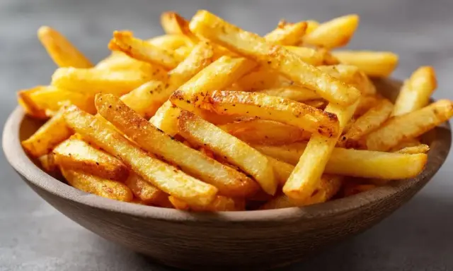 Knusprige Pommes aus dem Airfryer in einer Holzschale, perfekt gewürzt und goldbraun gebacken.