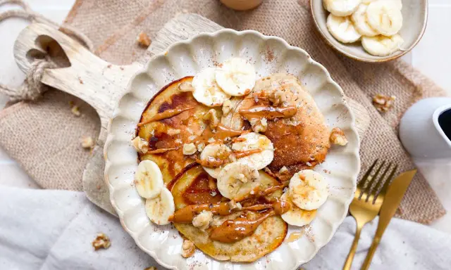Bananen Pancakes ohne Ei, garniert mit Bananenscheiben, Nüssen und einer cremigen Sauce. Ein köstlicher Brunch-Traum!