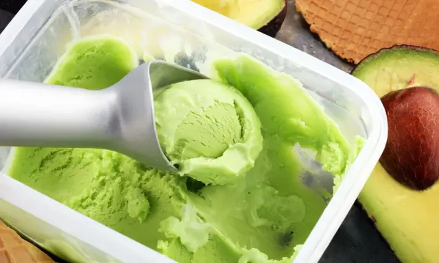 Cremiges, grünes veganes Eis, perfekt zum veganes Eis selber machen mit Mandelmilch. Avocados und Waffeln im Hintergrund.
