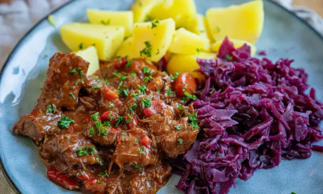 Herzhaftes Gulasch mit Kartoffeln und Rotkohl, inspiriert von Gulaschkanone Rezepten.