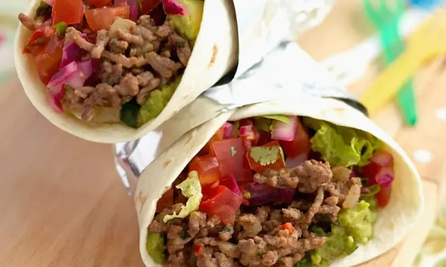 Zwei leckere wraps mit hackfleisch, Guacamole, Tomaten und roten Zwiebeln, eingewickelt in Folie.